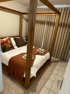 a bedroom with a wooden canopy bed in a room at Slaap Self Catering in Paarl