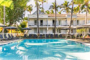 Una piscina con sillas y sombrillas frente a un edificio. en Hotel Exsel Alamanda, en Saint-Gilles-les-Bains