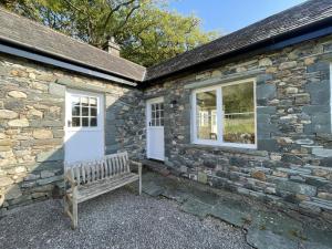 a stone house with a bench in front of it at Deer Close Cottage in Keswick