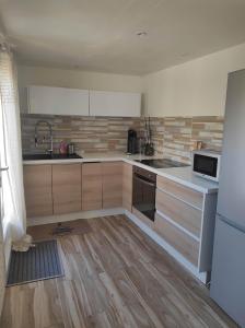 una cucina con armadi in legno, lavandino e frigorifero di La Casaflo a Florensac Altre 13 foto