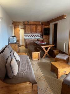 a living room with a couch and a kitchen at La Rosière centre, appartement 51 m2,3 pièces 2 chambres avec terrasse et parking couvert plein centre de la station, proche des pistes et commerces, ménage compris in La Rosière