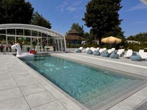 a swimming pool with a swan and chairs and a pavilion at Dukat Medical Spa in Dąbki