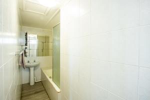 a white bathroom with a sink and a mirror at Seagull 401 in Margate +8 photos