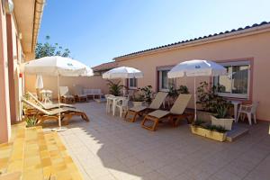 patio z krzesłami, parasolami i stołami w obiekcie Logis Hotel le Mirador w mieście Portiragnes