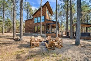 a wooden house with chairs and a fire pit at Family Getaway, Hot Tub, Firepit! in Broken Bow