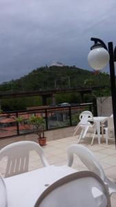 a patio with white chairs and a table and a light at Pousada Requinte in Vila Velha