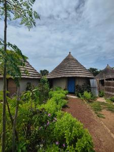 two huts with a tile roof in a garden at Campement Chez Doba in Dande