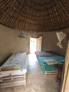 a room with two beds and a thatched roof at Campement Chez Doba in Dande +33 photos