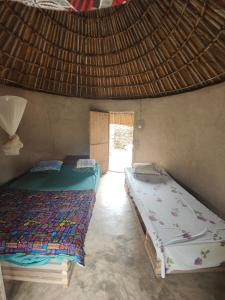 two beds in a room with a window at Campement Chez Doba in Dande