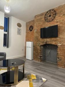 a living room with a fireplace and a tv on a brick wall at Icon Residencia Apartment in Manchester +11 photos
