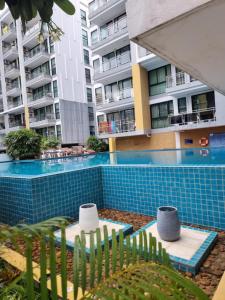 a swimming pool with two chairs and some buildings at Néo Condo Jomtien Pattaya in Jomtien Beach