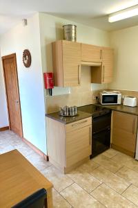 a kitchen with wooden cabinets and a microwave at Bluebell Cottage - Cedar Park in Grimsby +5 photos