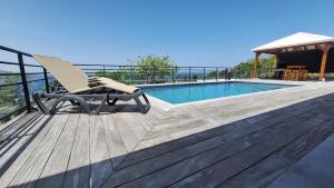 a chair sitting on a deck next to a swimming pool at Villa 4 étoiles Le Roc de Malendure in Bouillante