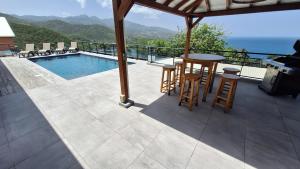 een terras met een tafel en stoelen naast een zwembad bij Villa 4 étoiles Le Roc de Malendure in Bouillante +27 foto's