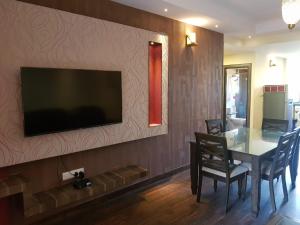 a dining room with a table and a television on a wall at Aquamarine Holidays Goa 2BHK Service Apartment 1 in Arpora