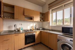 a kitchen with wooden cabinets and a washer and dryer at Natra Apartments in Kampala