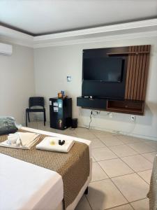 a hotel room with a bed and a flat screen tv at Kaa House Hotel in Carmópolis de Minas