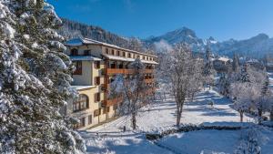 a building covered in snow with trees and mountains at Villars Lodge in Villars-sur-Ollon