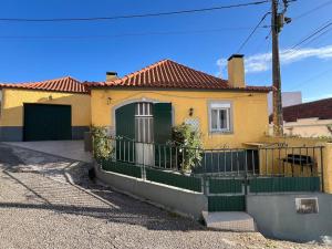 a yellow house with a green fence in front of it at Escapada amarela SPA et détente in Mariquiteira