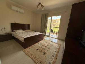 ein Schlafzimmer mit einem Bett, einem Teppich und einem Fenster in der Unterkunft Charming Apartment 2 Bedroom In El Rehab in Burg el-Ḥudûd