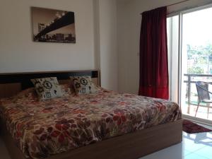 a bedroom with a bed with a red curtain and a window at KC Kamala Guesthouse in Kamala Beach +2 photos