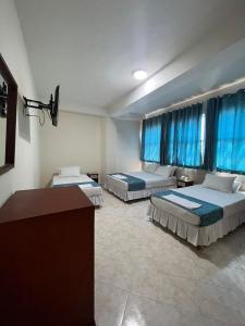 2 Betten in einem Hotelzimmer mit blauen Vorhängen in der Unterkunft Hotel El Andino in Cúcuta