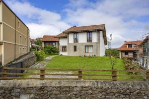 ein Haus mit einem Steinzaun vor einem Hof in der Unterkunft La Casuca, entre Mar y Montaña in Udias