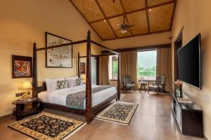 a bedroom with a bed and a flat screen tv at AamaGhati Wildlife Resort, Ranthambore in Sawāi Mādhopur