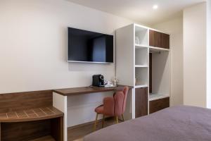 a room with a bed and a desk with a television at B&B Rais Luxury Rooms in Vieste