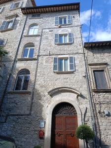 un edificio in pietra con porta marrone e finestre di Palazzo Antico ad Ascoli Piceno