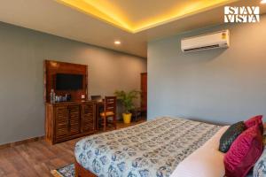 a bedroom with a bed and a tv and a desk at StayVista at Wildwoods Stone with Pool, Bathtub, Wi-Fi in Sawāi Mādhopur