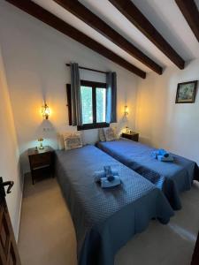 two beds in a room with blue sheets at Villa Sonrisa in Teulada