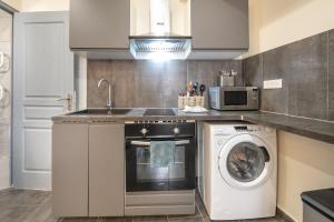 a kitchen with a washing machine and a microwave at Le Refuge du Val - Appartement vue montagne in Merlas +3 photos