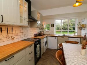 a kitchen with white cabinets and a table with a tableablish at Barton Lodge in Minehead