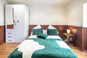 a bedroom with a large bed with green pillows at Le Refuge du Val - Appartement vue montagne in Merlas