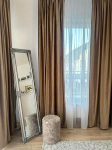 Un espejo y un taburete frente a una ventana en EmmasHome, en Sibiu