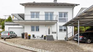 a white house with two cars parked in front of it at Ferienwohnung am Donauradweg in Tuttlingen
