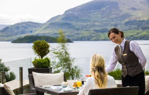 a woman cutting a persons hair on a table at The Europe Hotel & Resort in Killarney