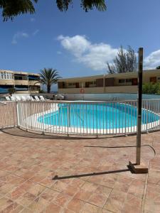 a swimming pool with a fence in front of a building at KALMA beach house,by Mahbo in Maspalomas