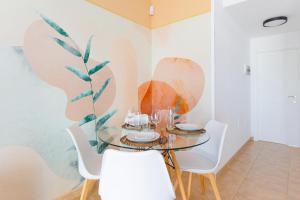 a dining room with a glass table and white chairs at Las Rocas 115 - Fuerteventura Golf Club in La Guirra +24 photos