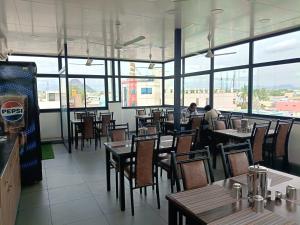 a dining room with tables and chairs and windows at HOTEL VARDHA Inn in Bhavāni