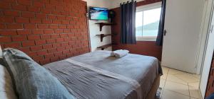 a bedroom with a bed and a brick wall at Residencial Marcelo e Irene in Florianópolis