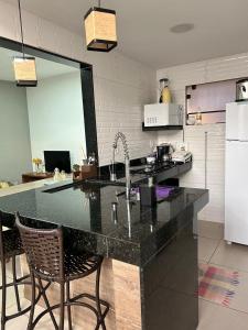 a kitchen with a large black counter top with chairs at Casa Praia Marina Búzios in Búzios