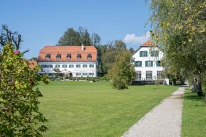 a large white house with a large yard at Hotel Aiterbach am Chiemsee in Rimsting