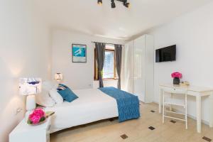 Un dormitorio blanco con una cama y un escritorio. en Old Town Suites and Rooms, en Poreč