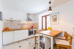 Una cocina con gabinetes blancos y una mesa de madera. en Old Town Suites and Rooms, en Poreč