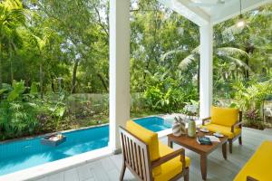 un patio con sillas amarillas y una piscina azul en Melhor Stays Villa - L-M305 Luxury 3BHK villa with Private pool, Anjuna, en Arpora