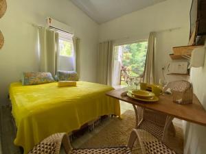 une chambre avec un lit jaune et une table avec des chaises dans l'établissement Maiga Pousada- Casa do Marcelino, à Fernando de Noronha