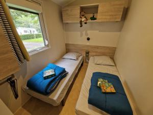 zwei Betten in einem kleinen Zimmer mit Fenster in der Unterkunft Camping Marmotel in Saint-Geniez-dʼOlt + 76 Fotos