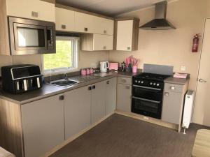 Una pequeña cocina con estufa y microondas. en Cute caravan Whitecliff Bay, en Bembridge 17 fotos más